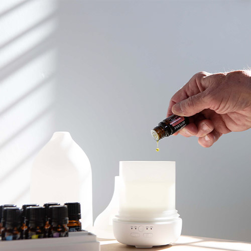 A person pouring essential oil into a diffuser