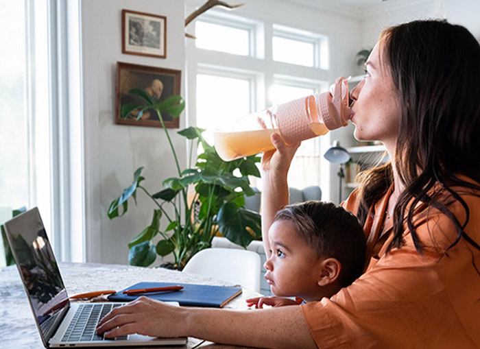 一個女人和一個孩子坐在放著筆記本電腦的桌邊