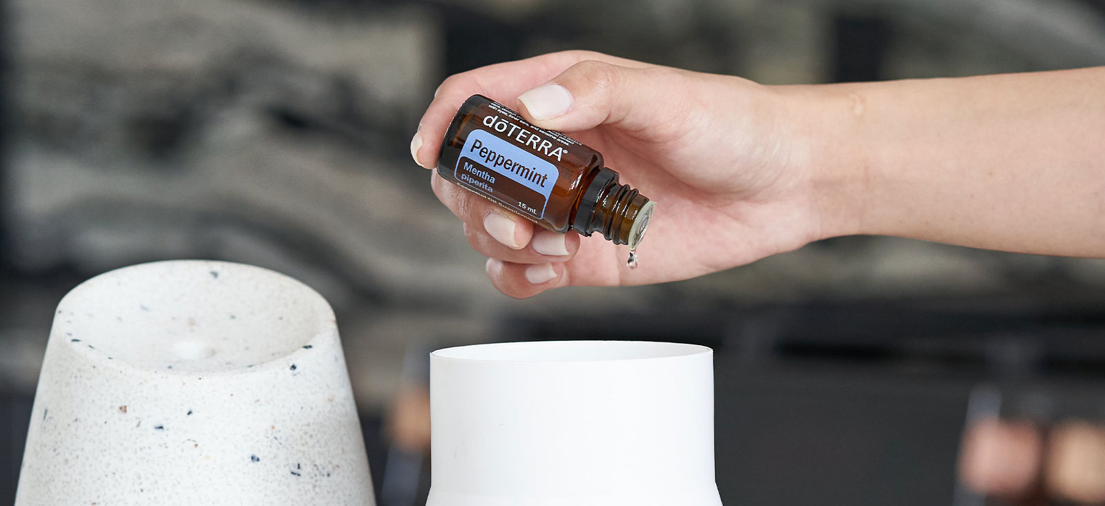 Someone adding peppermint drops to a diffuser