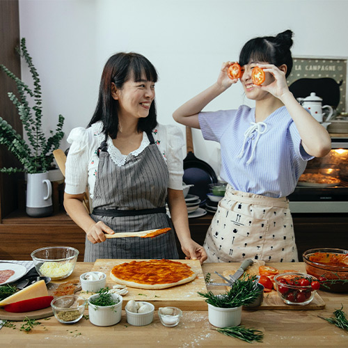 Mom and daughter having fun cooking a pizza